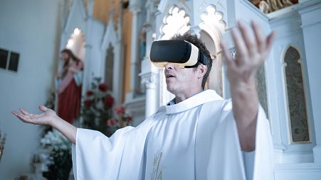 Image is a composite picture showing a priest wearing a VR headset. Churches are turning to the metaverse to bring the liturgy to a digital audience.