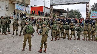 Soldats israéliens se tenant entre des colons et des résidents palestiniens du village de Burqah, en Cisjordanie, le 17 décembre 2021