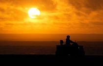 A person drives a quad bike along the beach as the sun sets in Nazare, Portugal, Saturday, Dec. 11, 2021.