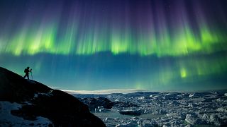 A photographer in North Greenland captures the perfect nighttime shot of northern lights, the starry night sky, and icebergs in the Ilulissat Icefjord.
