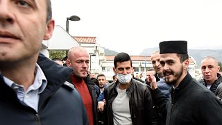 Serbian tennis player Novak Djokovic, center, wearing a face mask, arrives in the municipal building in Budva, Montenegro, Jan. 28, 2022. 