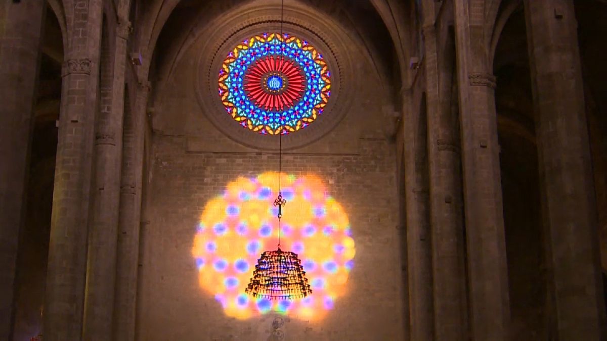 La luz proyecta colores azules, rojos y amarillos del rosetón mayor bajo el rosetón menor, 2/2/2022, Mallorca, España