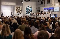 Auctioneer Oliver Barker leads an auction of The Macklowe Collection, alongside Andy Warhol's "Sixteen Jackies" (C) at Sotheby's on November 15, 2021 in New York.