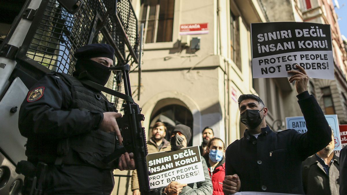 Members of human rights and migrant rights groups hold placards in Turkish and English as they gather in front of the Greek consulate in Istanbul