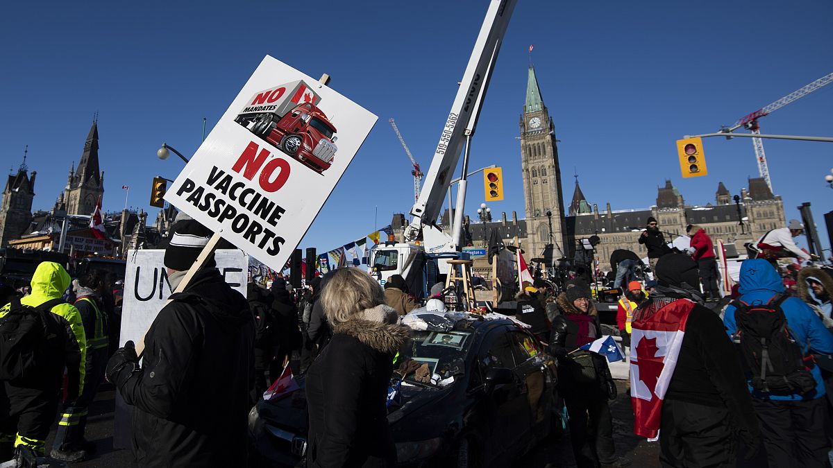 People hold signs and wave flags on Wellington Street in front of Parliament Hill at a protest against COVID-19 restrictions that has gridlocked downtown Ottawa, Feb. 5, 2022.