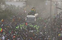The bus transporting Senegal's football team in the streets of Dakar, surrounded by a crowd