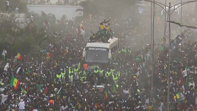 The bus transporting Senegal's football team in the streets of Dakar, surrounded by a crowd 