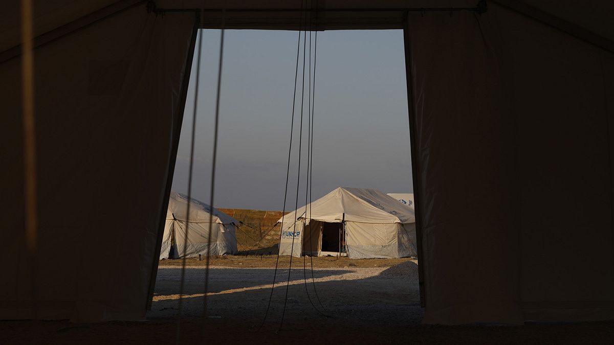A migrant sits inside a tent at the new temporary refugee camp at Karatepe, near Mytilene town, on the northeastern island of Lesbos