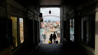 Um casal transporta malas de viagem em Lisboa