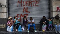 Des manifestants assis devant un graffiti où l'on peut lire en espagnol "Mort au FMI" après une manifestation à Buenos Aires (Argentine), mardi 8 février 2022.