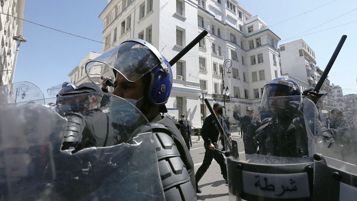 افراد من الشرطة الجزائرية يشهرون هراواتهم خلال مظاهرة في الجزائر - أرشيف