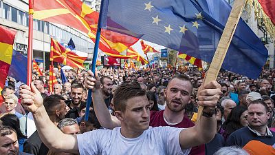 People waving national and EU flags gather at a rally in Skopje, April 2019