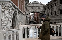 Homem com máscara passeia em Veneza, Itália