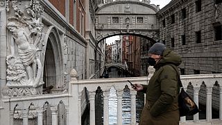 Homem com máscara passeia em Veneza, Itália