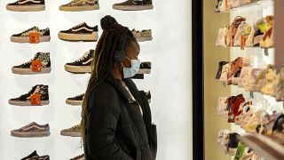 A woman wears a protective mask as she looks at shoes in Rue Neuve in Brussels, Belgium, Saturday, Nov. 27, 2021.