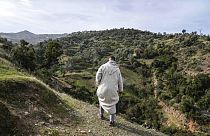 رجل يسير عبر تلة بقرية إيغران خلال مهمة إنقاذ ريان، البالغ من العمر خمس سنوات، بعد أن سقط في بئر عميق، ضواحي شفشاون، شمالي المغرب، الجمعة 4 فبراير 2022.