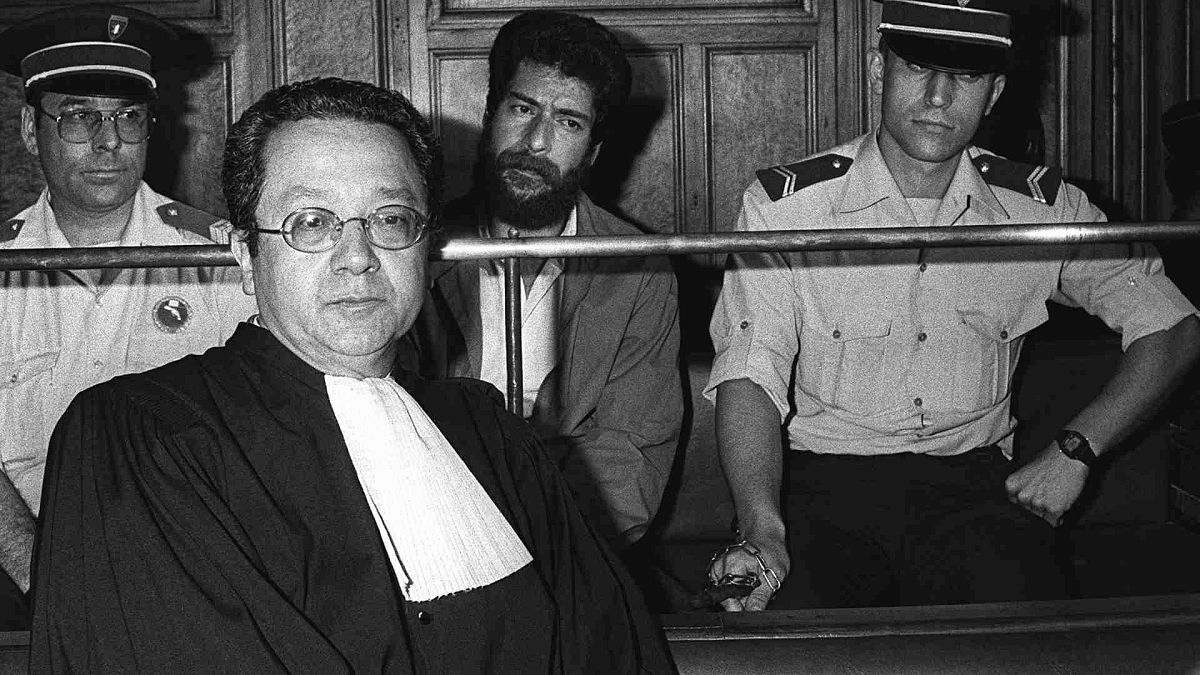 جورج إبراهيم عبد الله (أسفل الصورة في الوسط) يجلس أثناء محاكمته في محكمة ليون، بجانب محاميه جاك فرجيس ، فرنسا 3 يوليو / تموز 1986  