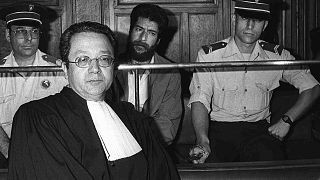 جورج إبراهيم عبد الله (أسفل الصورة في الوسط) يجلس أثناء محاكمته في محكمة ليون، بجانب محاميه جاك فرجيس ، فرنسا 3 يوليو / تموز 1986