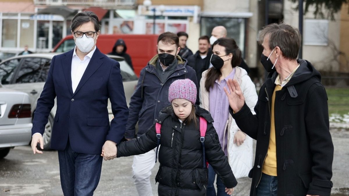 The President of the Republic of North Macedonia, Stevo Pendarovski, holds the hand of Embla Ademi as he walks her to school on February 7, 2022.