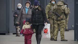 A woman holds a child's hand as they cross from Ukrainian government to pro-Russian separatists controlled territory in Stanytsia Luhanska.