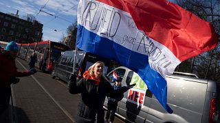 Una mujer con una bandera neerlandesa en la que se lee "libertad para nuestros hijos" en la entrada de la sede del Gobierno en La Haya, Países Bajos, el 12 de febrero de 2022.
