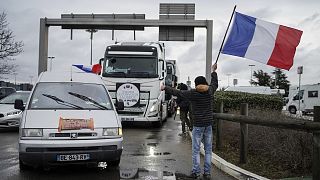 Francia zászlóval integet egy tiltakozó egy járművekből álló konvojnak Lyonban
