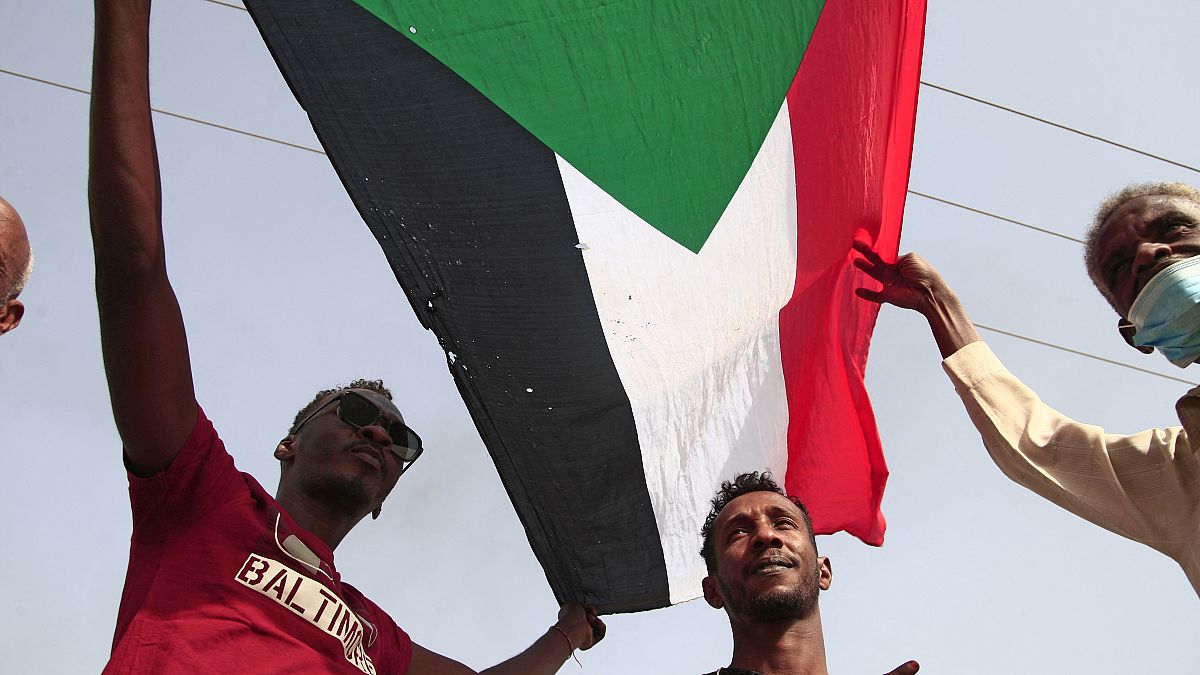 رجال يرفعون العلم السوداني ويهتفون بشعارات خلال مظاهرة تطالب بالحكم المدني وتندد بالإدارة العسكرية في جنوب العاصمة الخرطوم في 10 فبراير 2022.