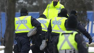 Police arrest a person as they walk the line to remove truckers and supporters protesting against COVID-19 restrictions in Windsor, Ontario, Canada, Feb. 13, 2022.