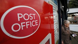 A woman walks out of a Post Office in London, Thursday, Oct. 10, 2013. 