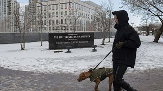 A person walks with their dog in front of the U.S. Embassy in Kyiv, Ukraine, Saturday, Feb. 12, 2022.