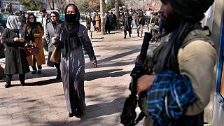 امرأة تمر بجانب مسلح من طالبان في كابول، 13 فبراير 2022