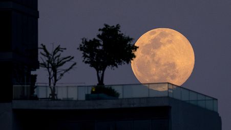 The Wolf Moon, the first full moon of the year, rises behind an apartment building in Bangkok on January 17, 2022.