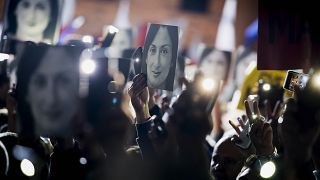 People hold pictures of slain journalist Daphne Caruana Galizia during a 2019 protest.