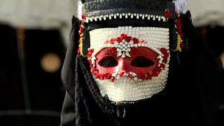 A reveller wears a highly decorated Venetian Bauta mask