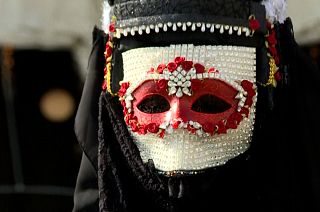A reveller wears a highly decorated Venetian Bauta mask