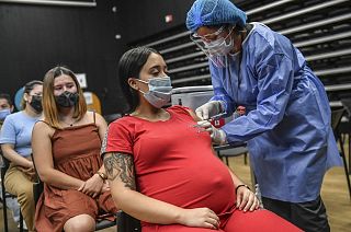 A pregnant woman is inoculated with the Pfizer-BioNTech vaccine against COVID at a vaccination center in Medellin, Colombia.