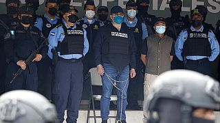 El expresidente Juan Orlando Hernández esposado de pies y manos y custodiado por varios agentes