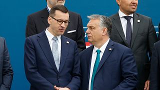 Poland's Prime Minister Mateusz Morawiecki, left, and Hungary's Prime Minister Victor Orban share a word as they line up for a group picture prior to a meeting in Portugal