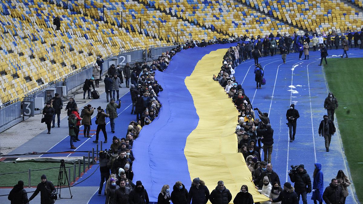 Ukrainians deploy a giant national flag in a Kyiv stadium