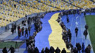 Ukrainians deploy a giant national flag in a Kyiv stadium
