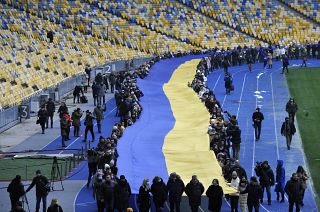 Ukrainians deploy a giant national flag in a Kyiv stadium