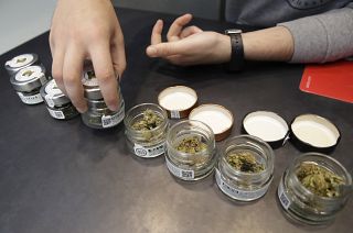 In this Thursday, June 6, 2019 a shop assistant opens jars of cannabis buds at a cannabis light store in Milan, Italy.
