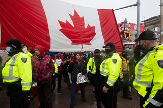 Police are followed by yelling protesters as they attempt to hand out a notices to protesters in Ottawa, on Thursday, Feb. 17, 2022.