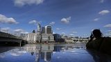A woman is silhouetted as she takes a phone call, as the skyline of London is reflected in the polished stones of London Bridge during sunny weather in London, Tuesday, Sept.