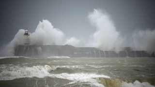 Wellen brechen über dem Leuchtturm von Newhaven an der Südküste Englands