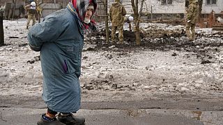 An elderly lady walks by as members of the Joint Centre for Control and Coordination on ceasefire of the demarcation line