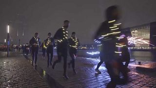 Un grupo de corredores llevan puestas luces LED mientras avanzan por las calles de Copenhague