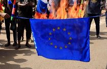 Demonstrators burn EU flag