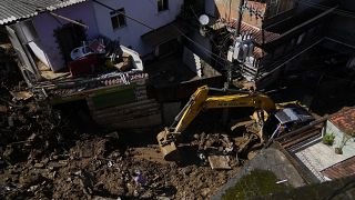 Munkagéppel takarítják el a sarat a házak közül a Rio de Janeiro állambeli Petrópolisban 2022. február 17-én, két nappal a földcs