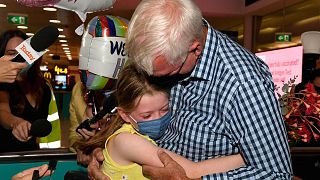 A man hugs his granddaughter upon arriving at Sydney International Airport after Australia reopened its borders for the fully vaccinated